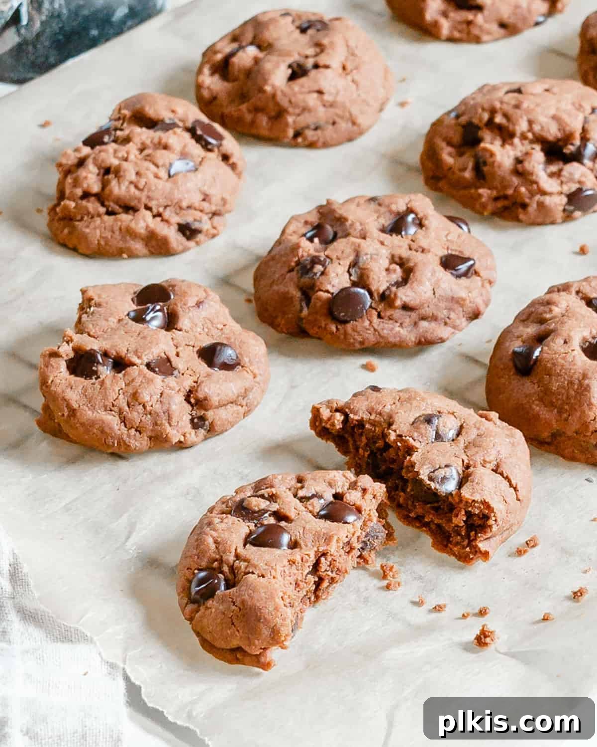 Peppermint Chocolate Chip Vegan Delights 8 A close-up shot of several finished Vegan Double Chocolate Peppermint Cookies, one halved to show its moist interior, resting on parchment paper.