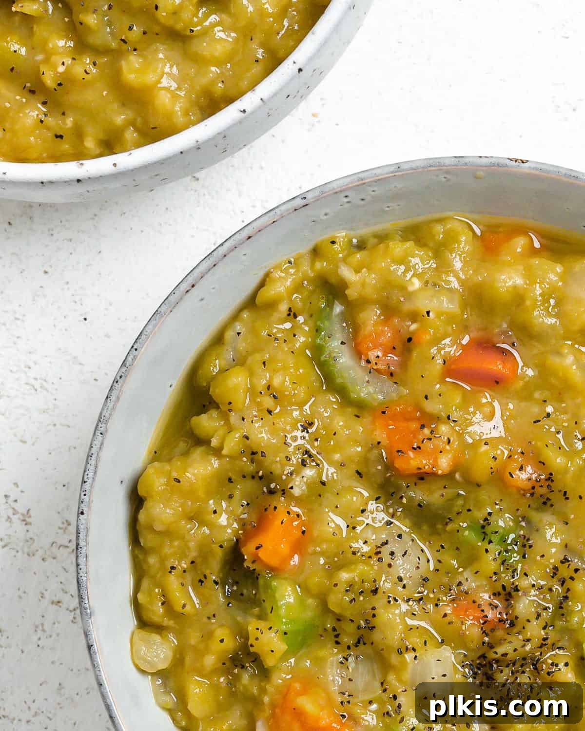Golden Vegan Split Pea Goodness 6 A close-up shot of a bowl of creamy Vegan Split Pea Soup, garnished with a sprinkle of fresh parsley, showcasing its rich texture.