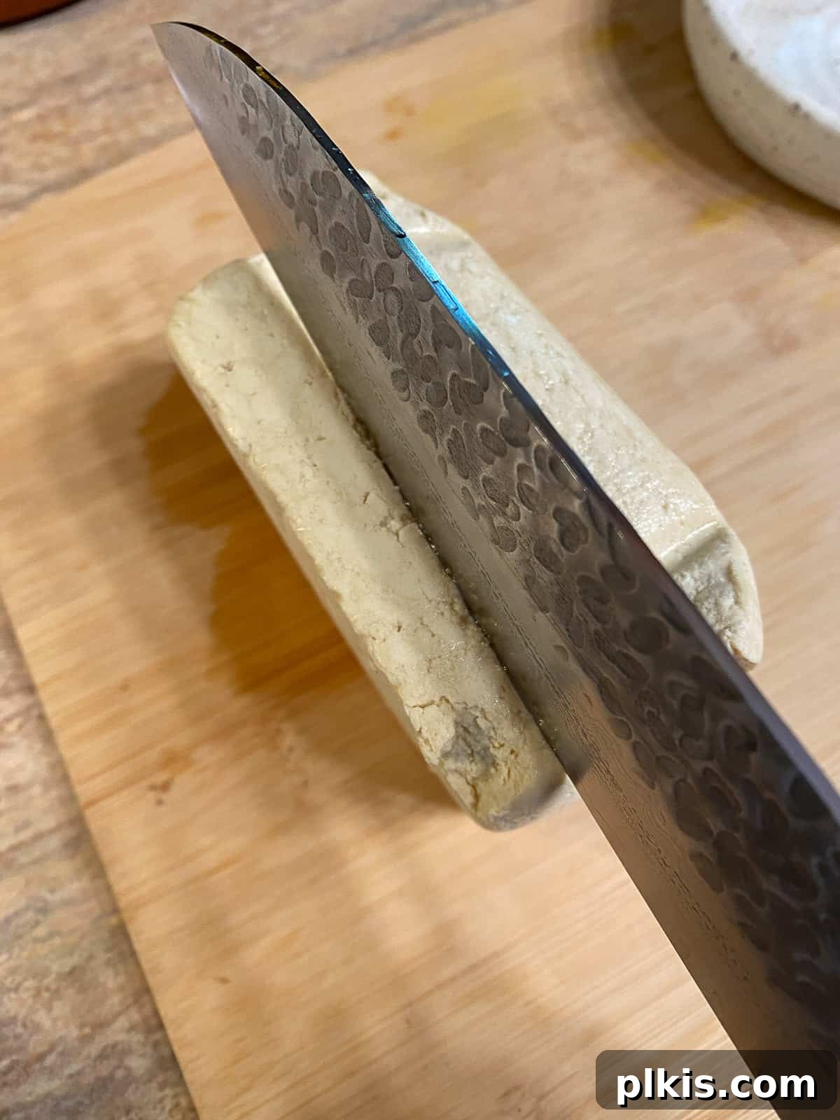Pesto Tofu Sandwich: Simple Savory Superb 4 A block of extra-firm tofu being carefully sliced into ½-inch thick pieces on a cutting board, ready for seasoning.