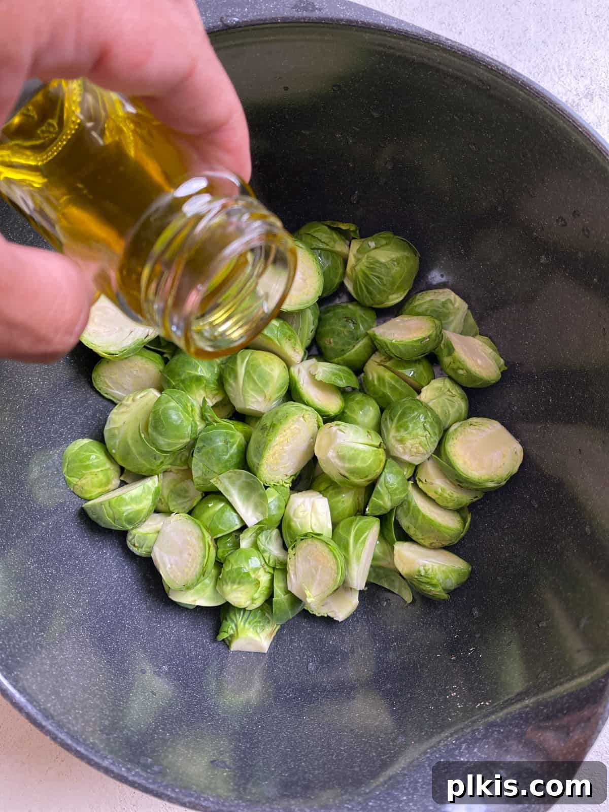 Tangy Cranberry Roasted Brussels Sprouts 4 Process shot of pouring olive oil onto a baking sheet of Brussels sprouts.