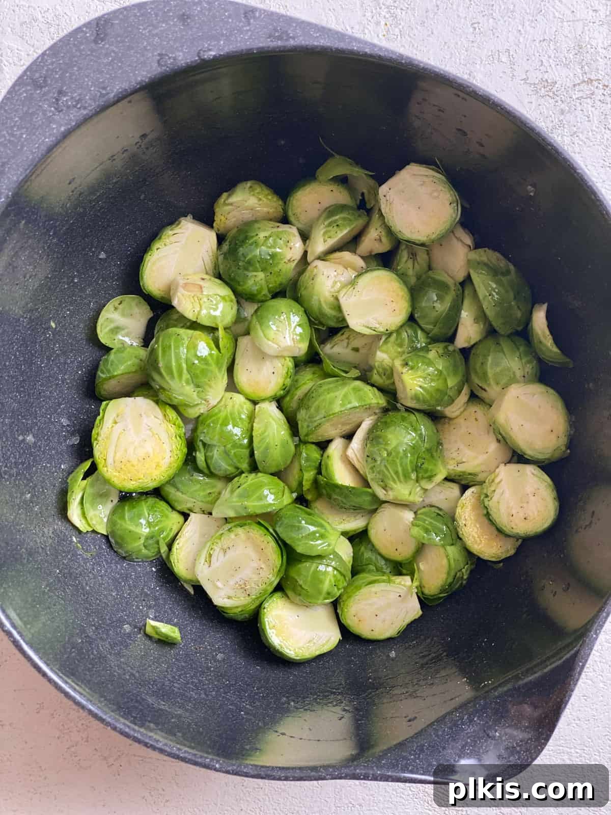 Tangy Cranberry Roasted Brussels Sprouts 6 Process shot of tossing Brussels sprouts with oil, salt, and pepper on a baking sheet.