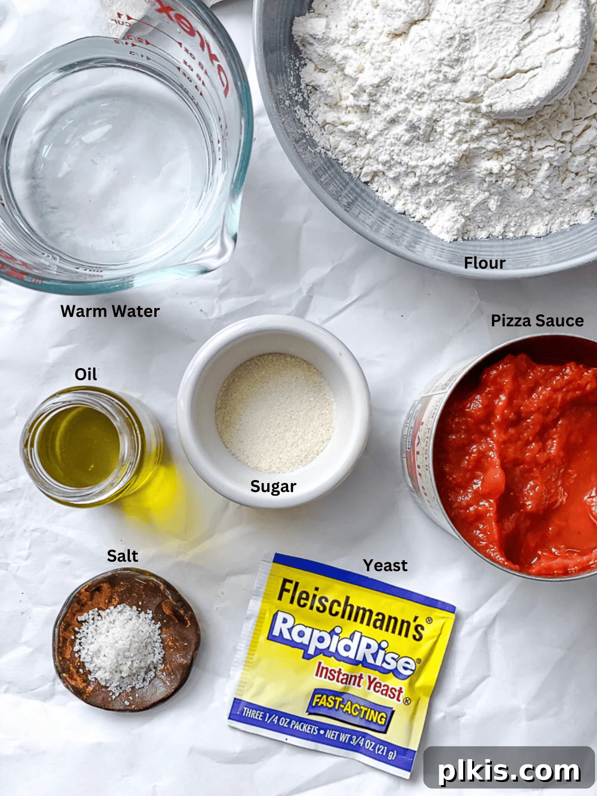 Simple Plant-Based Pizza Crust 3 Collection of ingredients for Easy Vegan Pizza Dough arranged on a white surface, including flour, yeast, sugar, salt, water, and oil
