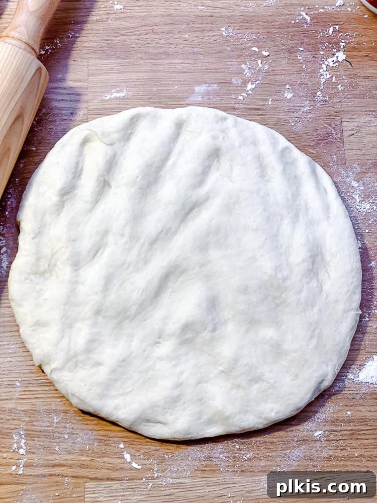 Simple Plant-Based Pizza Crust 7 Process shot showing a pizza dough being flattened and shaped by hand on a surface