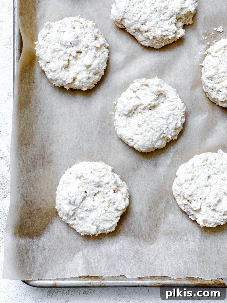 Effortless Plant-Based Biscuits in Minutes 13 Unbaked vegan biscuits are arranged on a parchment-lined baking dish, ready for the oven.