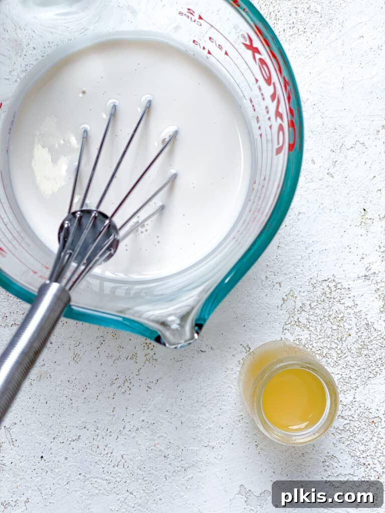 Effortless Plant-Based Biscuits in Minutes 4 A close-up shot of plant milk and apple cider vinegar being whisked together in a glass bowl to create vegan buttermilk.