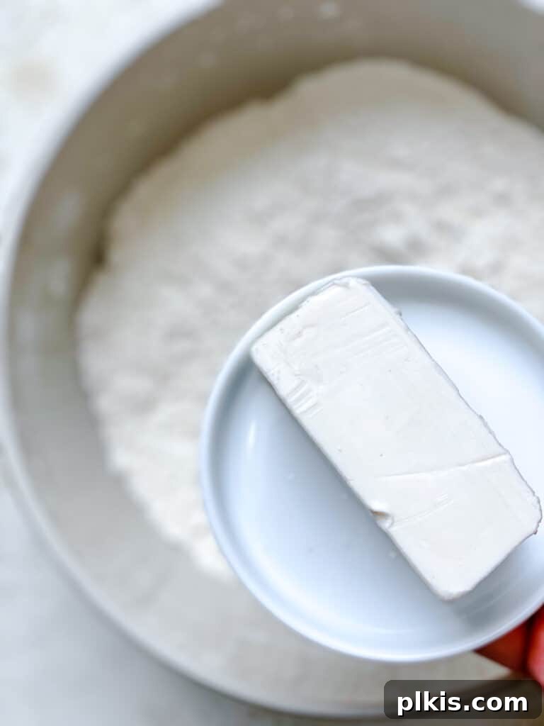 Effortless Plant-Based Biscuits in Minutes 6 Process shot of grated frozen vegan butter being added to the dry flour mixture in a bowl.
