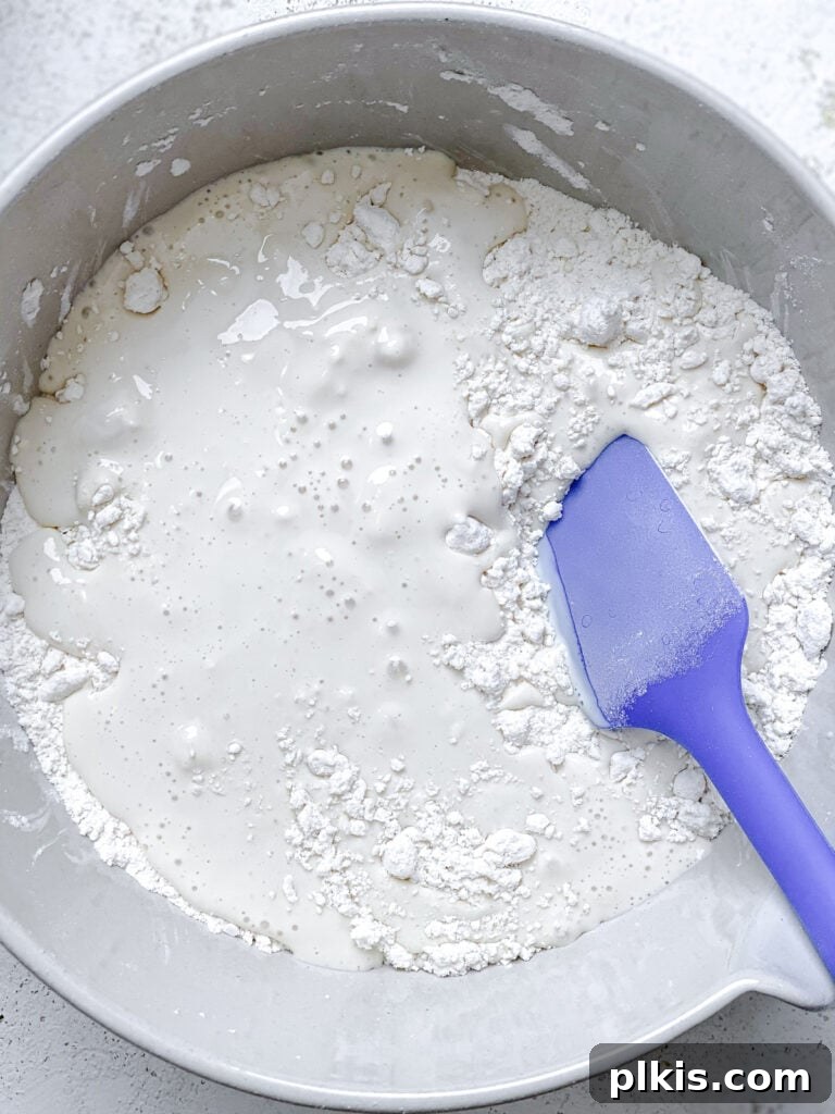 Effortless Plant-Based Biscuits in Minutes 10 A shaggy dough forms as ingredients are gently mixed by hand in a bowl, avoiding overmixing.
