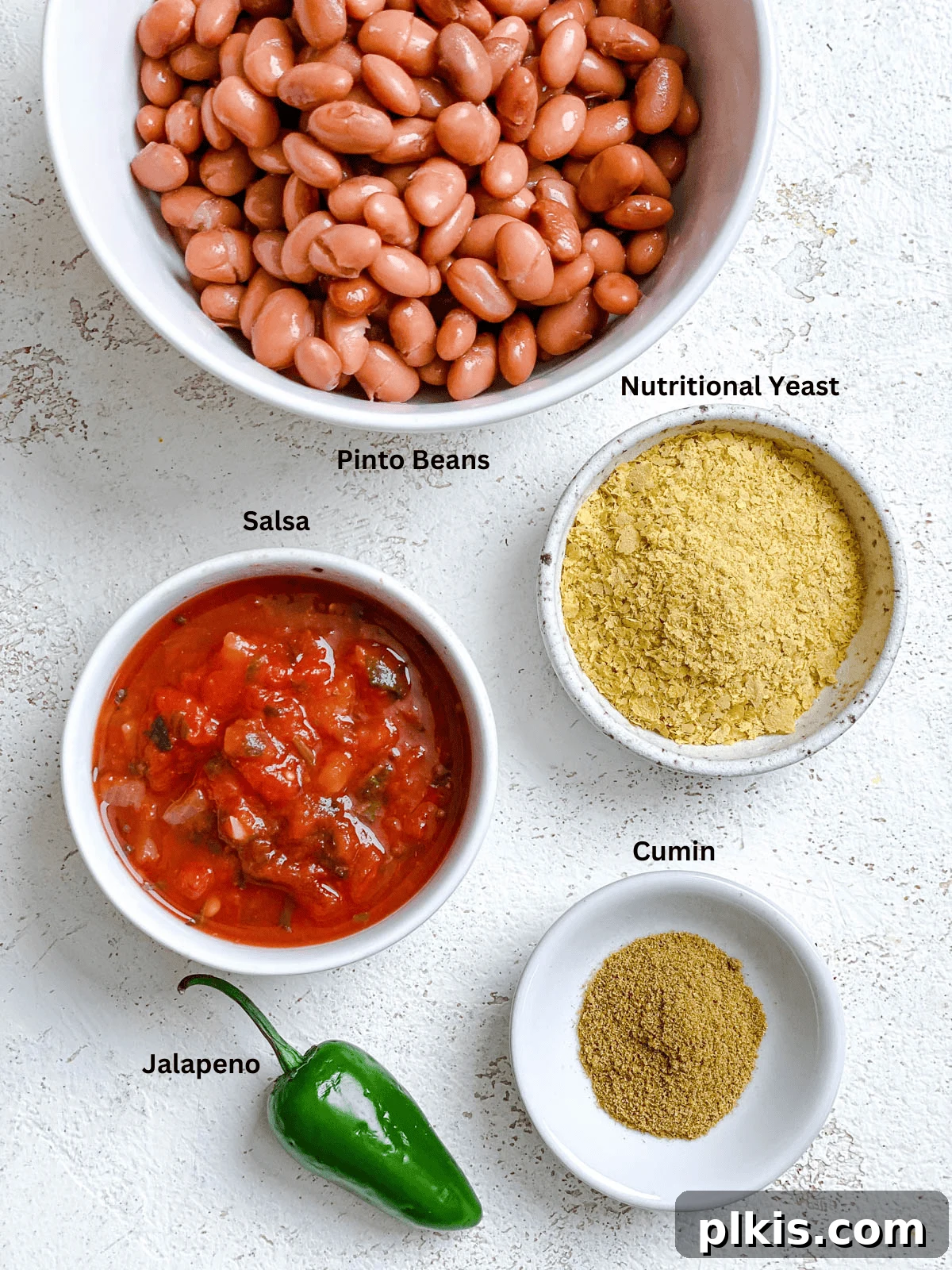 Creamy Pinto Delight 3 All the necessary ingredients for Mexican Pinto Bean Dip laid out on a clean white surface, perfectly measured and ready for preparation.