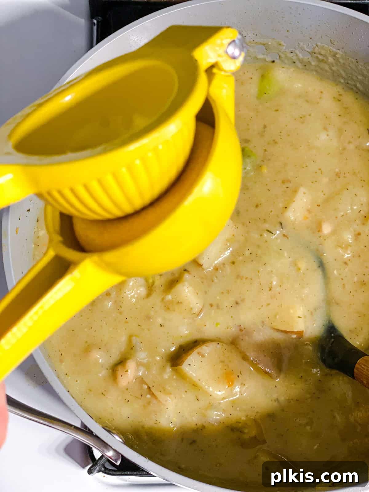 Process shot of a chef adding a squeeze of fresh lemon juice to the creamy asparagus soup, enhancing its flavor profile.