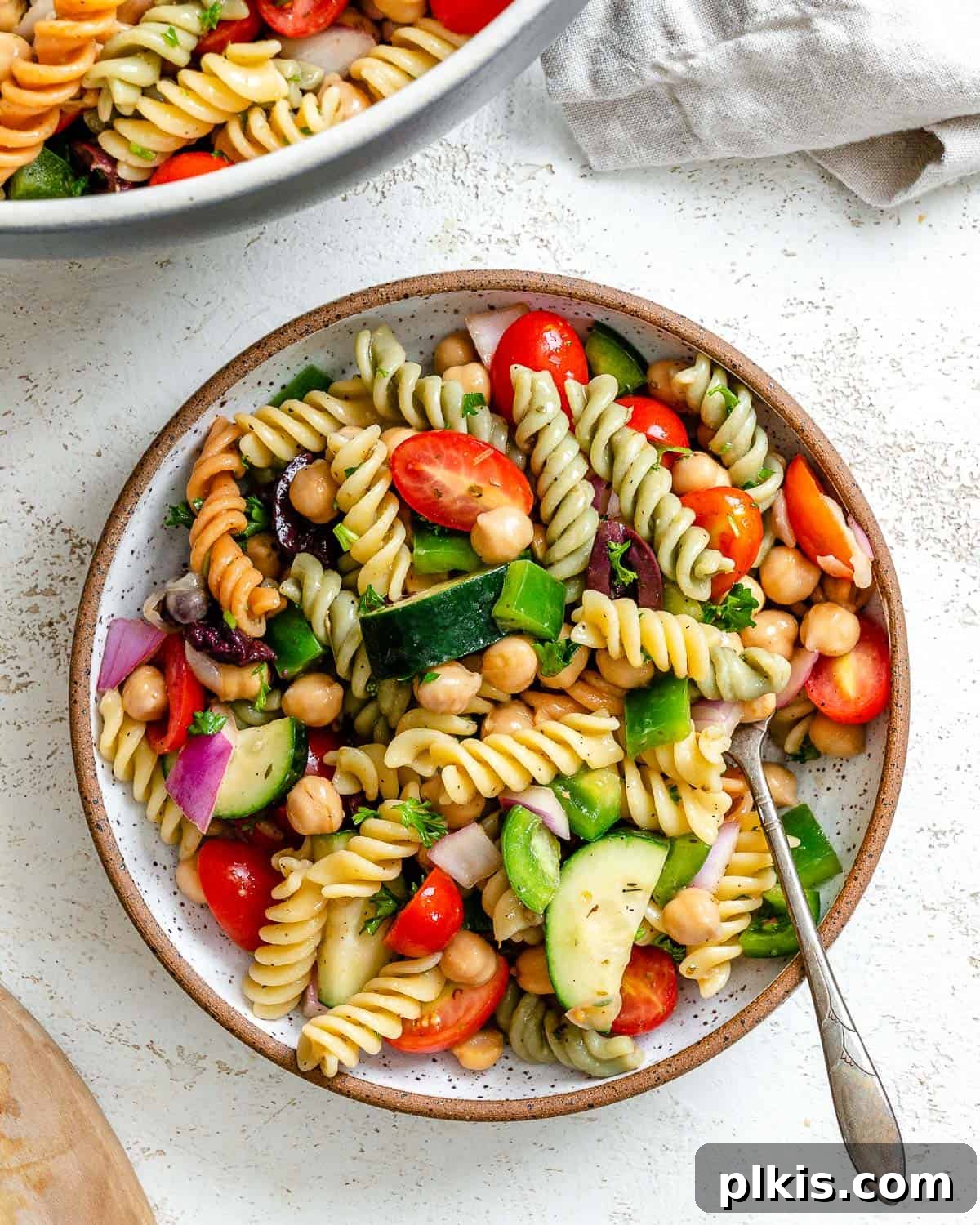 A vibrant Mediterranean Vegan Pasta Salad, perfectly plated and ready to be enjoyed, showcasing fresh ingredients against a clean white background.