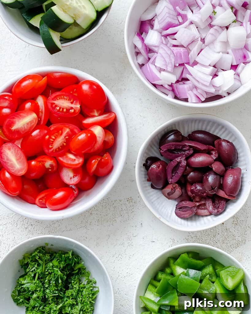 Ingredients for Mediterranean Vegan Pasta Salad, neatly arranged in separate bowls on a white surface, prior to mixing.