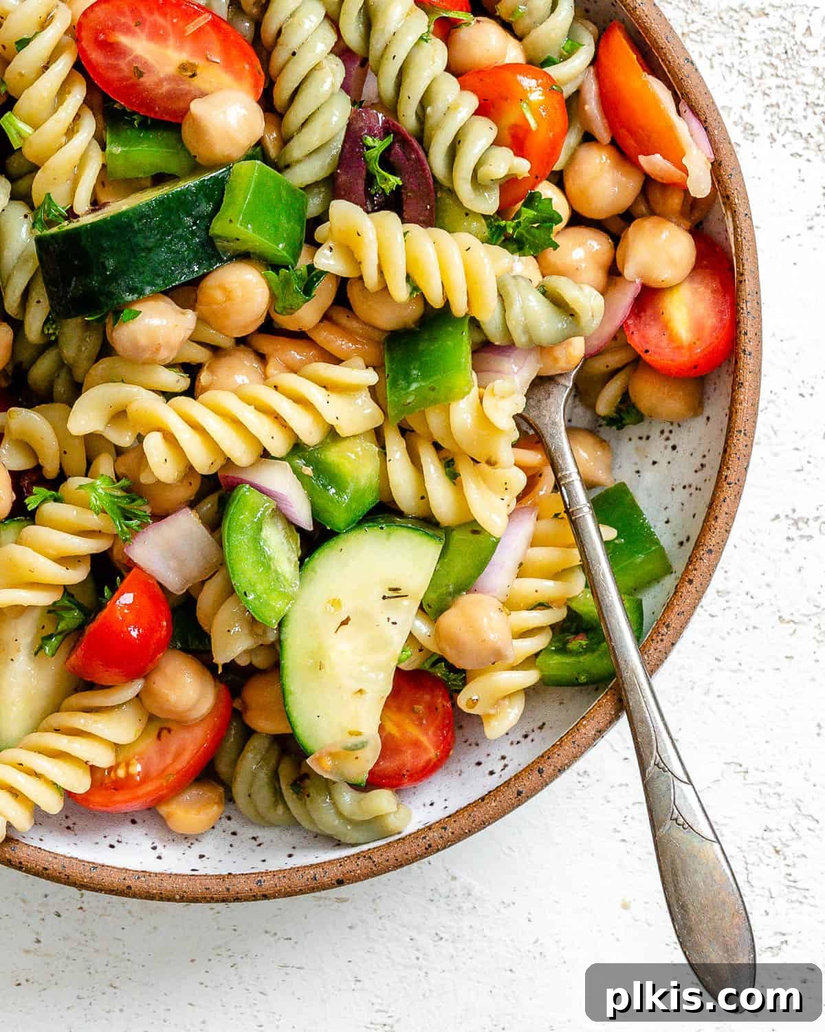 Another beautiful shot of the completed Mediterranean Vegan Pasta Salad, artfully presented on a plate against a white backdrop.