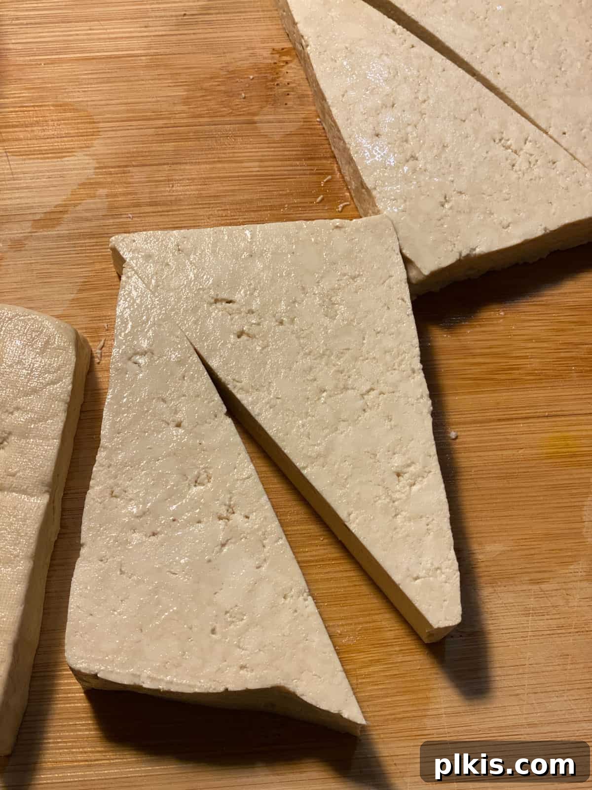 Vibrant Lemon Basil Tofu 4 Tofu cut into triangular wedges on a cutting board, ready for cooking.