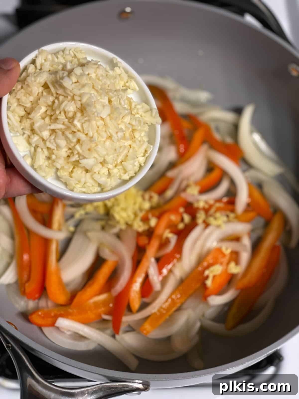 Vibrant Lemon Basil Tofu 6 Minced ginger being added to a hot frying pan with sautéing onions and bell peppers.