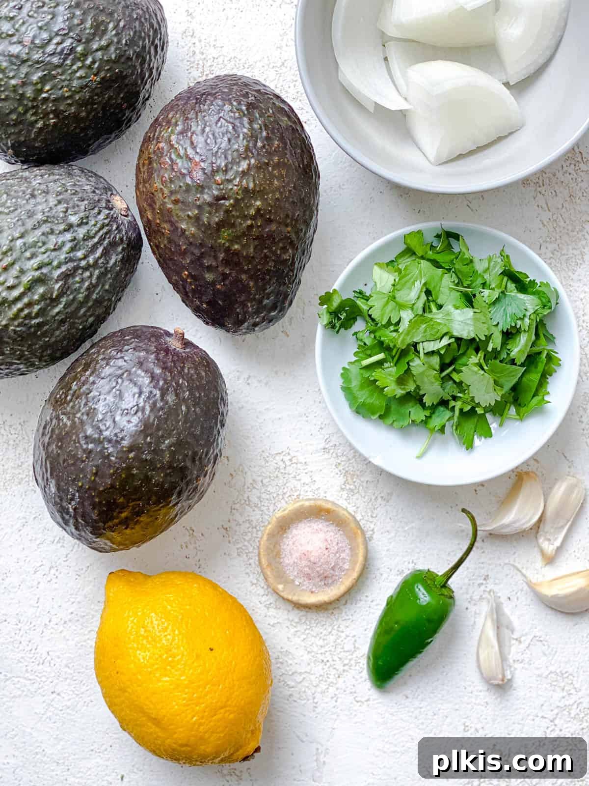 Instant Mexican Avocado Crema 3 Ingredients for Mexican Avocado Crema measured out against a white background, including avocados, onion, garlic, cilantro, lemon, salt, and a jalapeno