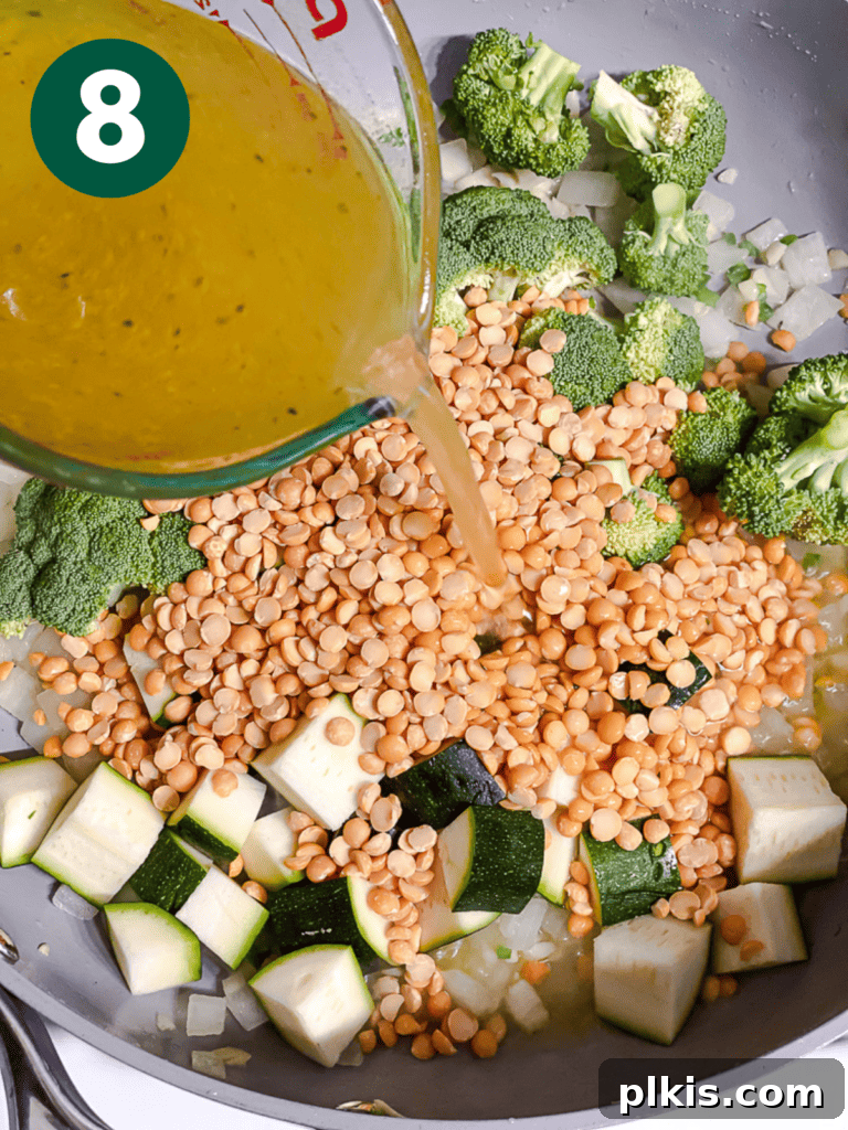 Golden Turmeric Veggie Split Pea Stew 11 Vegetable broth being poured into the pan to simmer the ingredients.