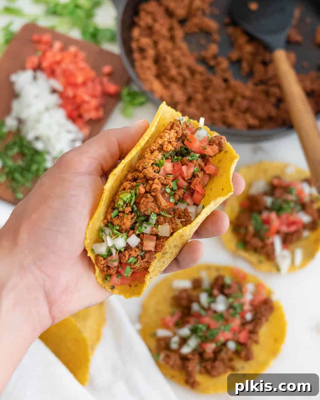Tacos Beyond Belief 2 Delicious Impossible Tacos served in mini corn tortillas with fresh cilantro, diced onions, and tomatoes, showcasing a vibrant plant-based meal.