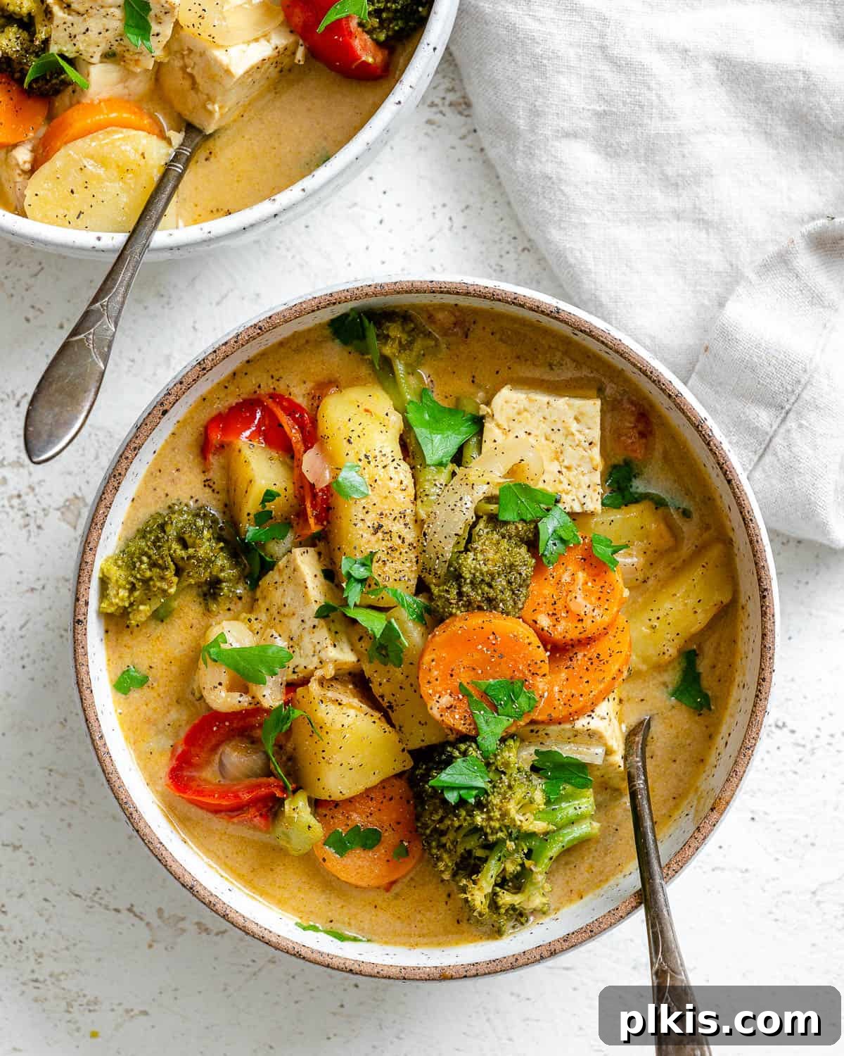 Creamy One-Pot Vegan Yellow Tofu Curry 2 A vibrant bowl of creamy one-pot tofu yellow curry, garnished with fresh herbs and served over fluffy rice, with a spoon in the bowl.