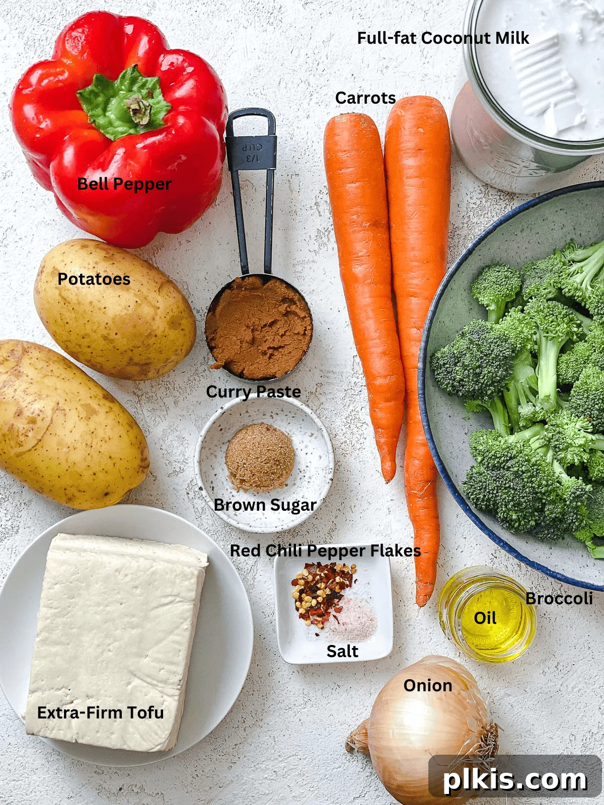 Creamy One-Pot Vegan Yellow Tofu Curry 3 A curated display of fresh, raw ingredients for a delicious yellow tofu curry, including cubed tofu, sliced vegetables, and a jar of yellow curry paste.