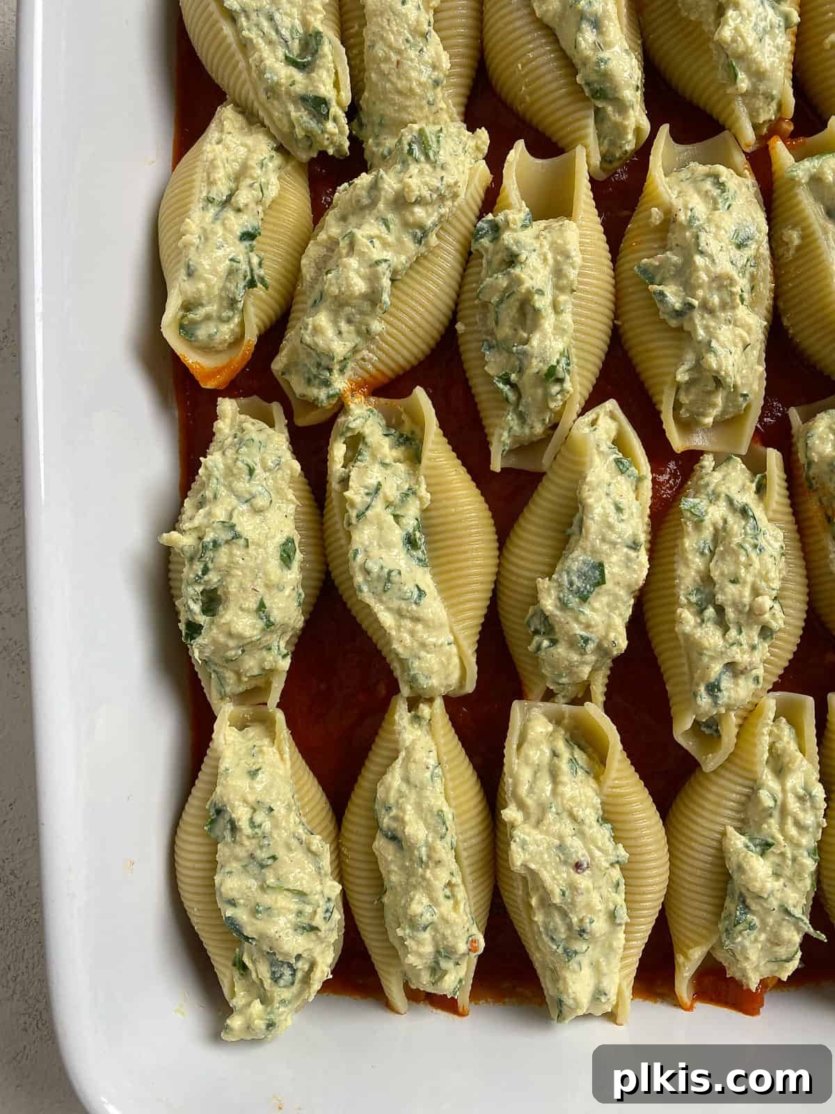 Creamy Vegan Stuffed Shells 14 A baking dish filled with neatly aligned, unstuffed jumbo pasta shells, ready for the next steps.
