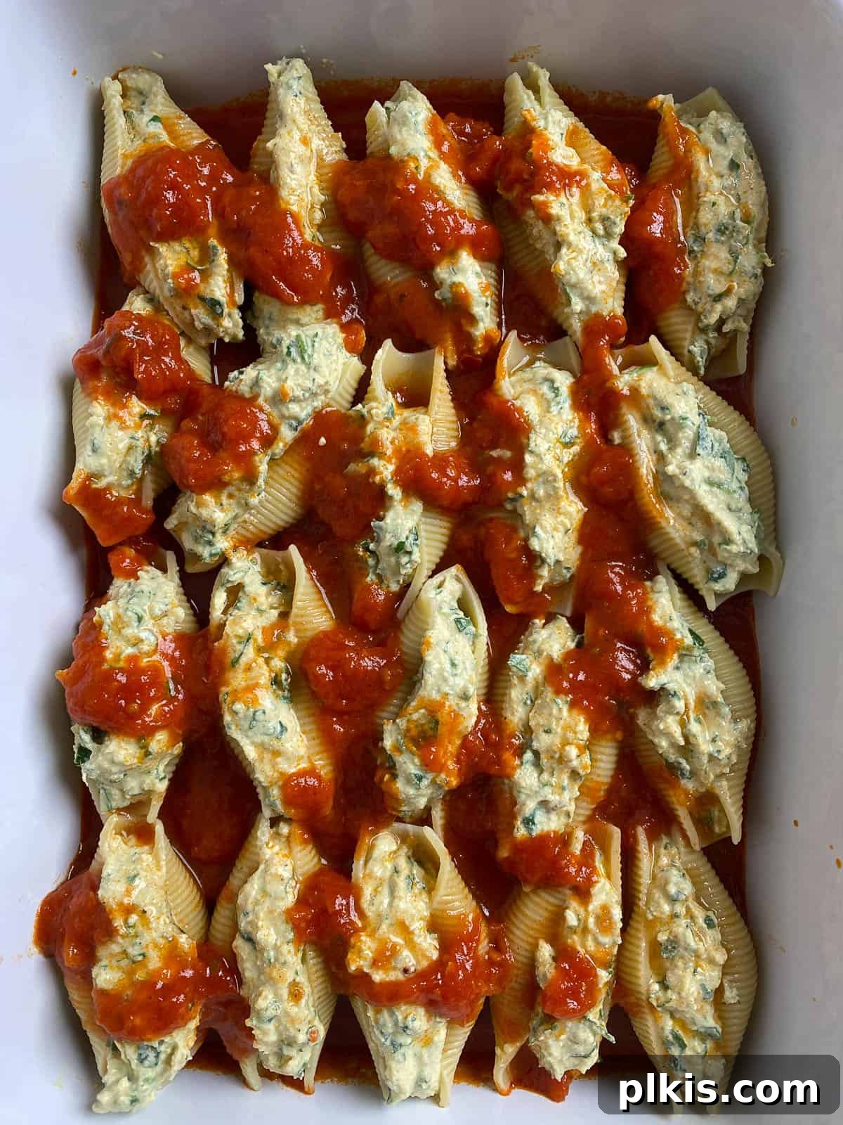 Creamy Vegan Stuffed Shells 16 A close-up shot of the stuffed shells in the baking dish after marinara sauce has been added, showing their readiness for baking.