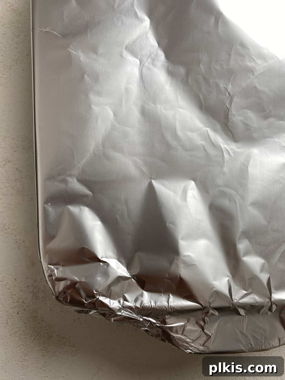Creamy Vegan Stuffed Shells 17 A foil-covered baking dish of stuffed shells, ready to be placed into the oven, resting on a light surface.