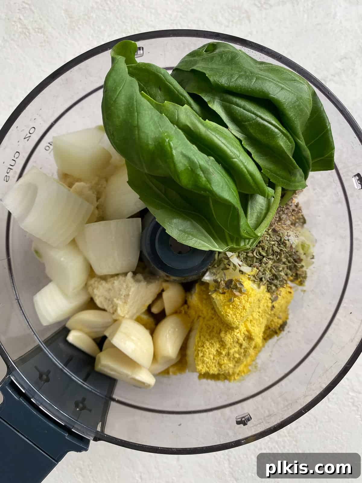 Creamy Vegan Stuffed Shells 6 The initial ingredients for the tofu ricotta (tofu, onion, garlic, herbs, spices, nutritional yeast, lemon juice) added into a food processor bowl.