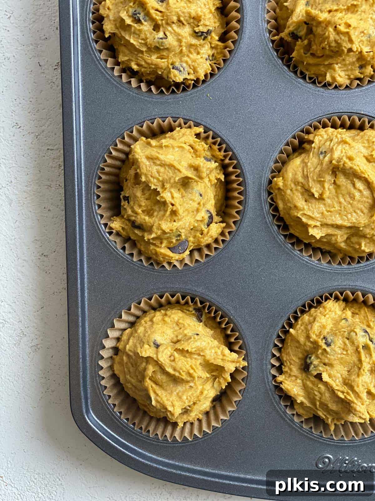 Spiced Vegan Pumpkin Chocolate Chip Muffins 12 process of adding unbaked muffin batter to muffin tin