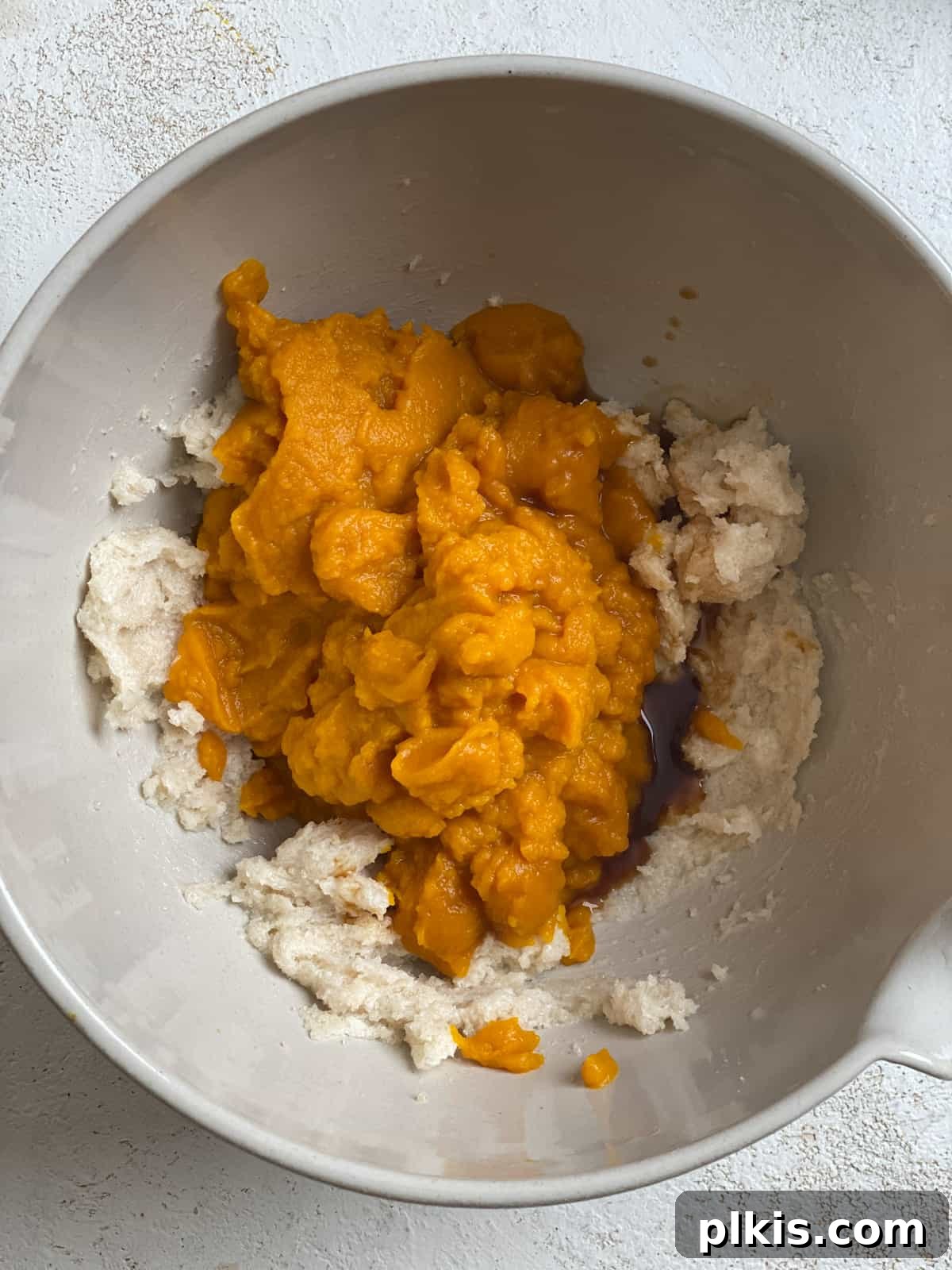Spiced Vegan Pumpkin Chocolate Chip Muffins 6 process of adding pumpkin to bowl of ingredients in a white bowl