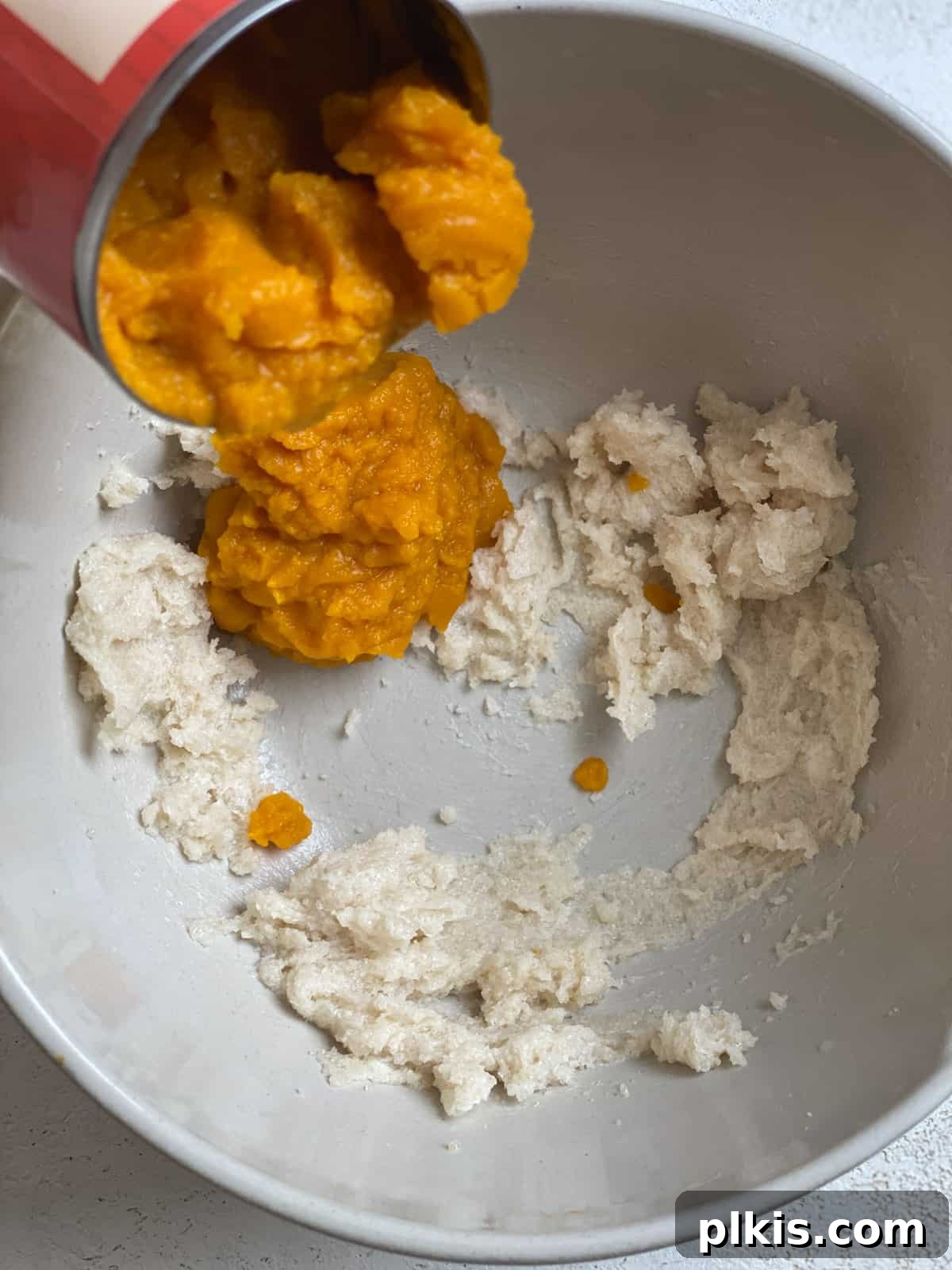 Spiced Vegan Pumpkin Chocolate Chip Muffins 8 process of adding pumpkin to bowl of ingredients in a white bowl