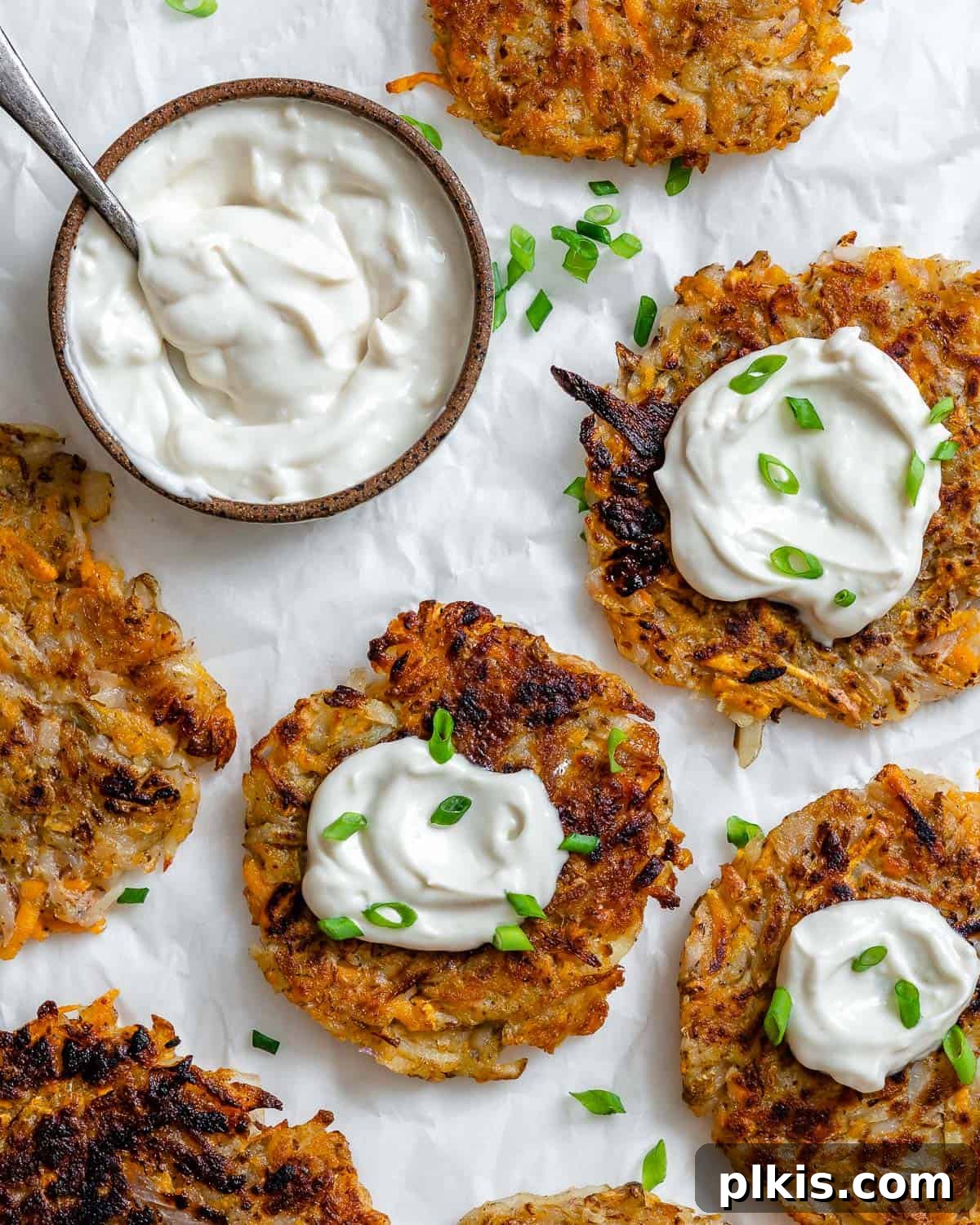 Golden Sweet Potato Latkes 2 Several completed Sweet Potato Latkes on a white surface, garnished with fresh herbs