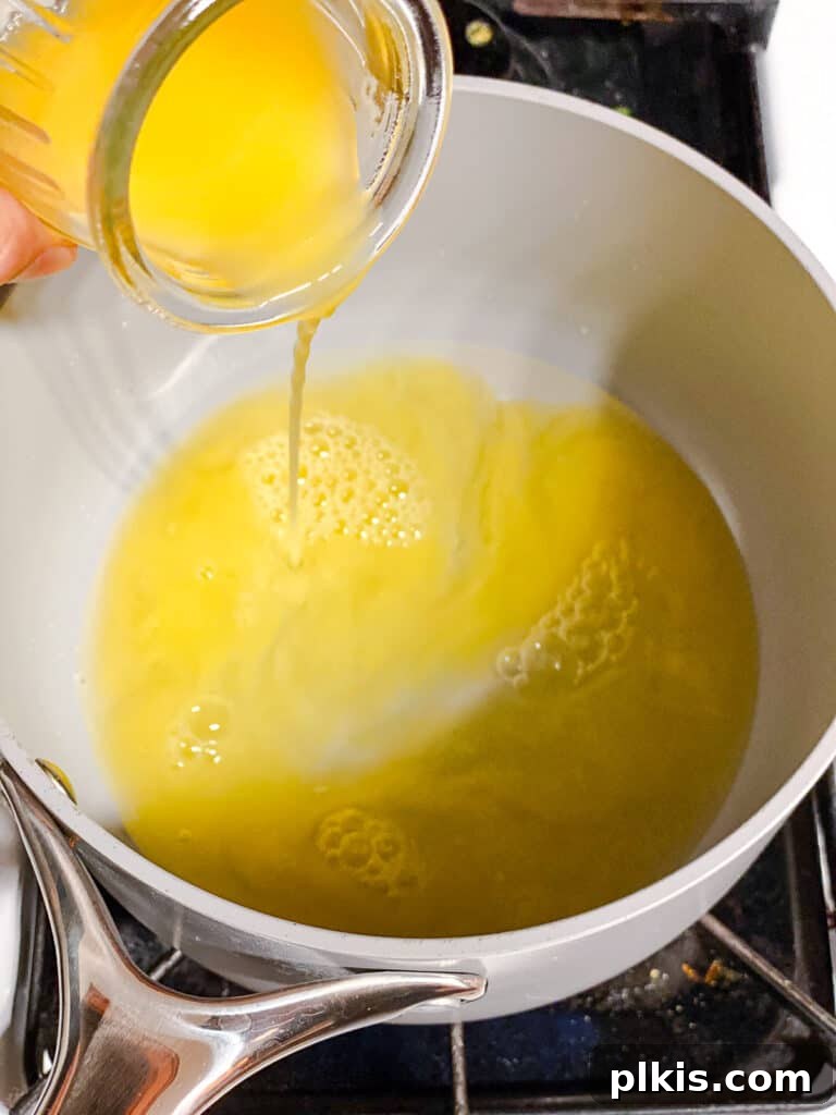 Process shot of pouring lemon juice into the pot with sugar, illustrating the first step of making cranberry sauce.