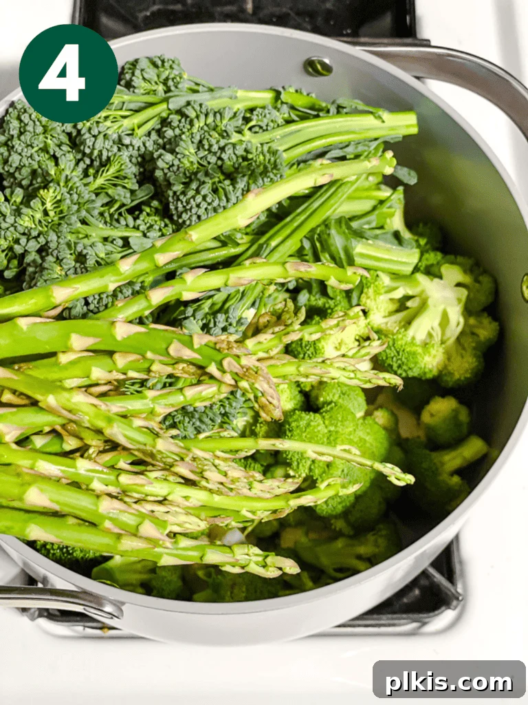 Christmas Tree Veggie Tray 7 Step-by-step image of adding asparagus to a pot for steaming.