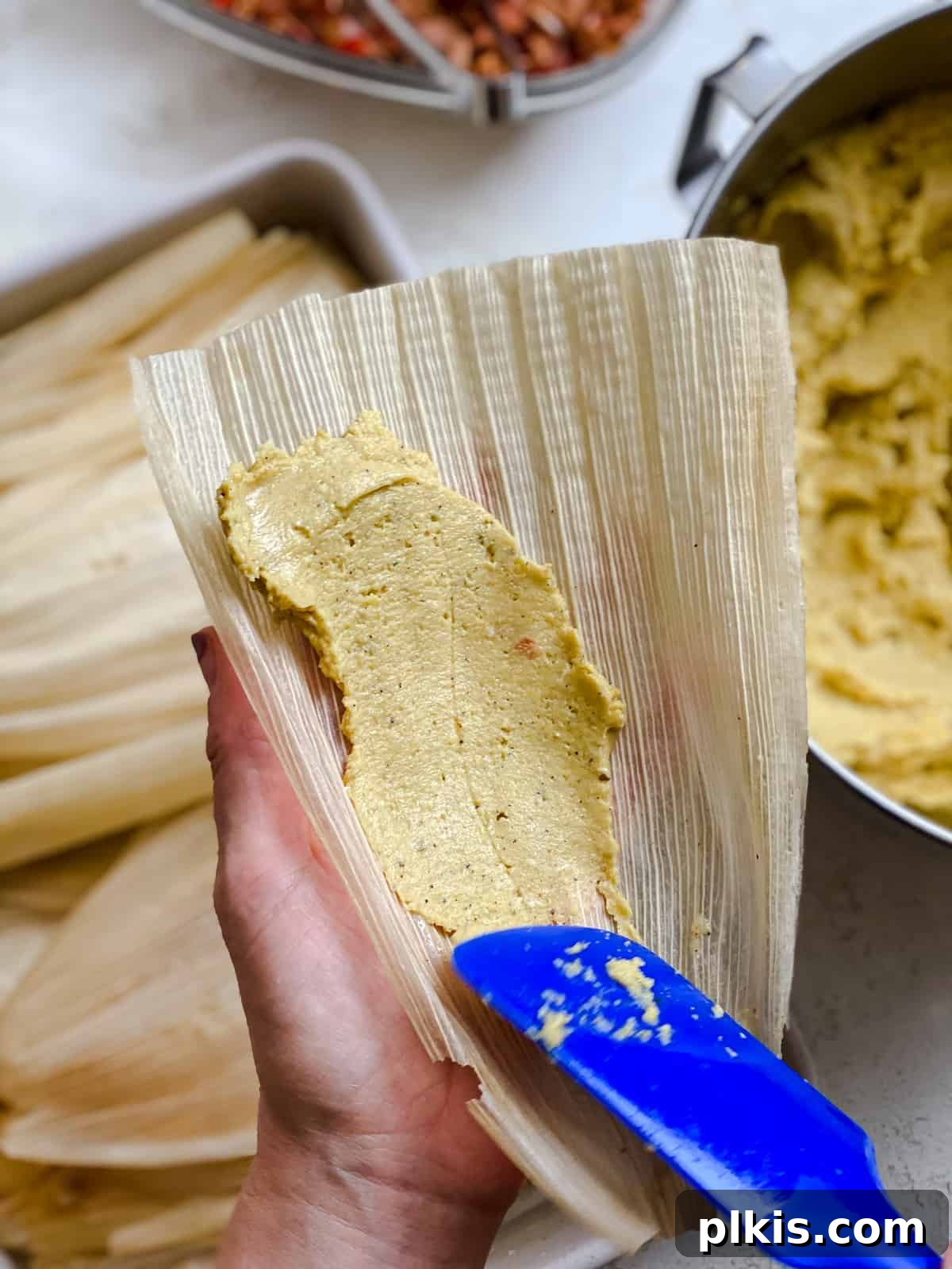 Crafting Perfect Vegan Tamales 11 Process shot of spreading tamale masa dough onto a corn husk.