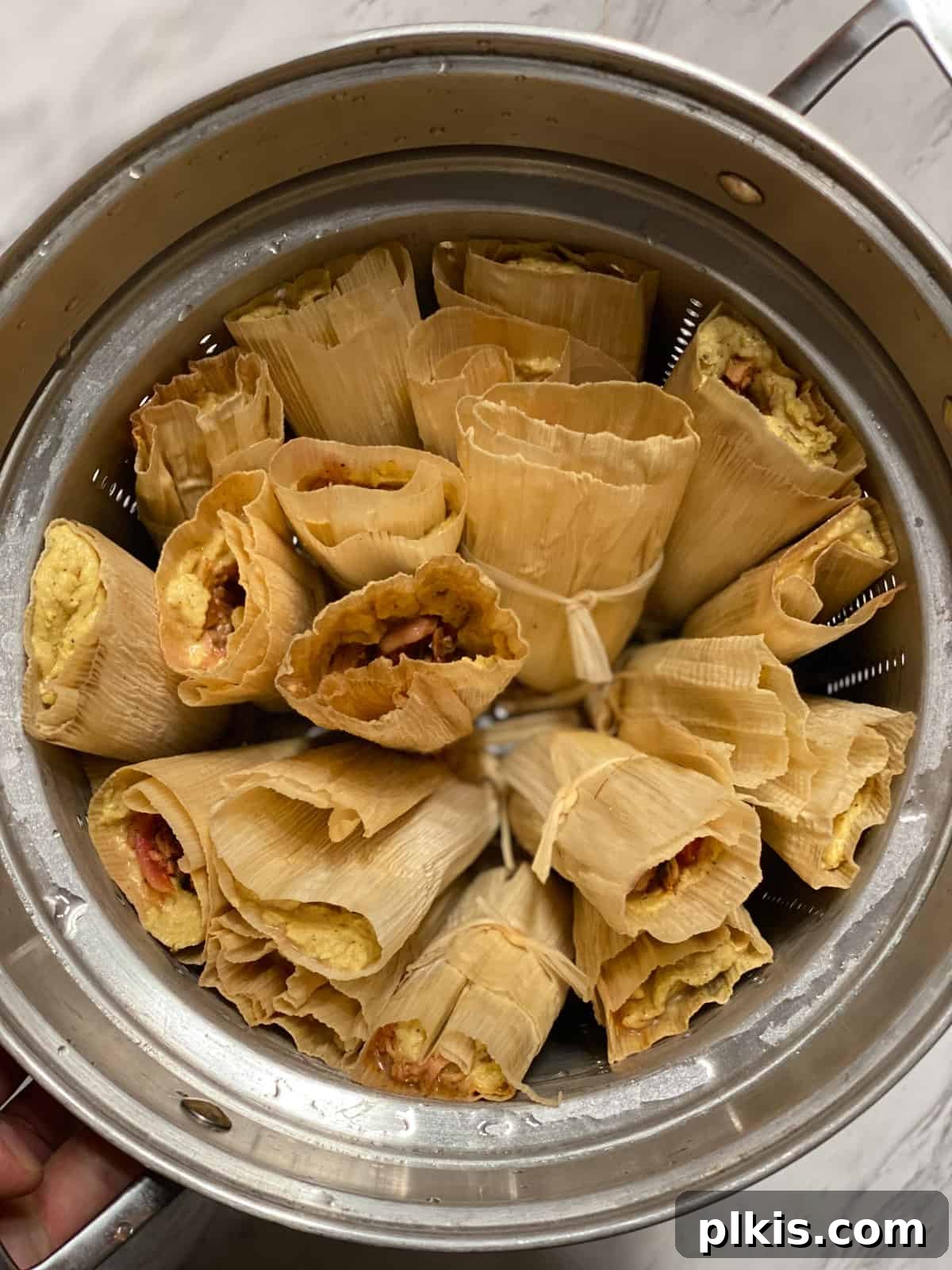Crafting Perfect Vegan Tamales 15 Process shot showing tamales arranged upright in a large steamer pot.
