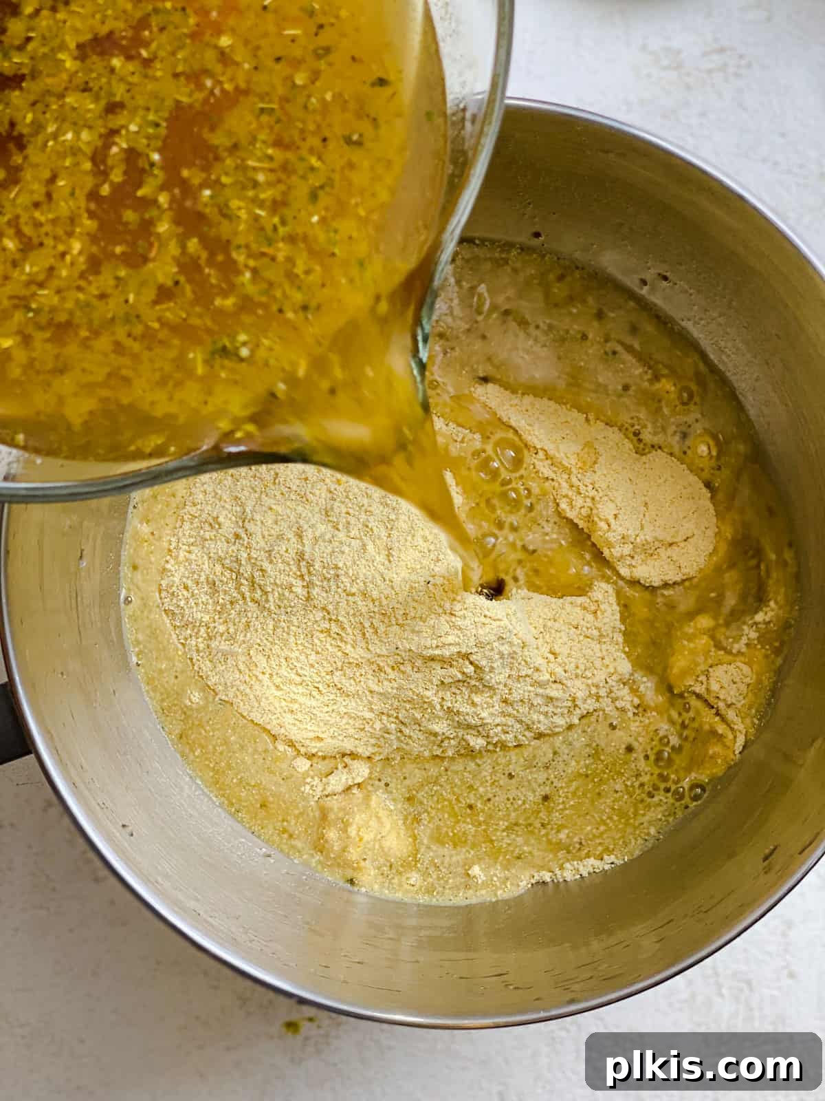 Crafting Perfect Vegan Tamales 5 Process shot of pouring vegetable broth into a mixing bowl with masa ingredients.