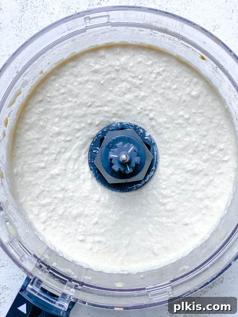 Quick & Creamy Hummus 6 A view of the hummus ingredients being processed into a smooth, creamy paste inside a food processor.
