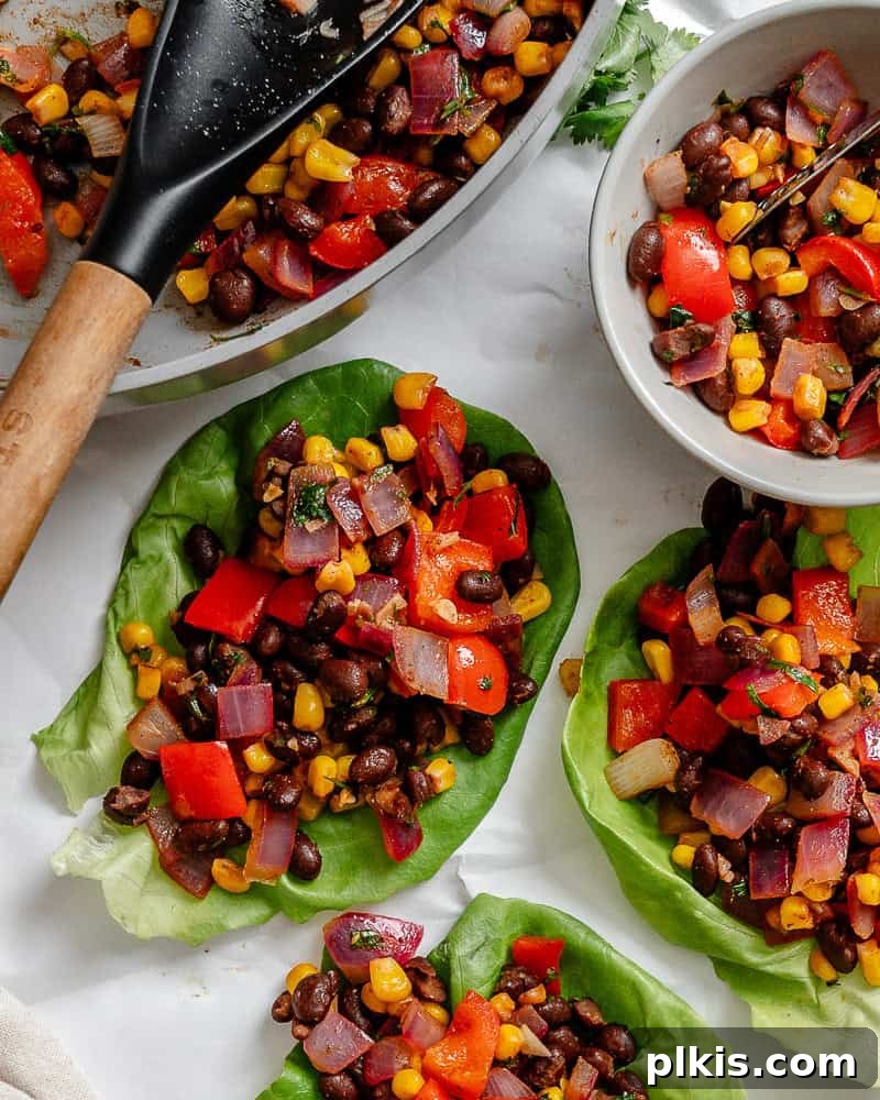 Zesty Bean and Corn Lettuce Wraps 2 Several beautifully arranged Vegetarian Lettuce Wraps with a rich black bean and corn filling on a pristine white surface, garnished with fresh cilantro.