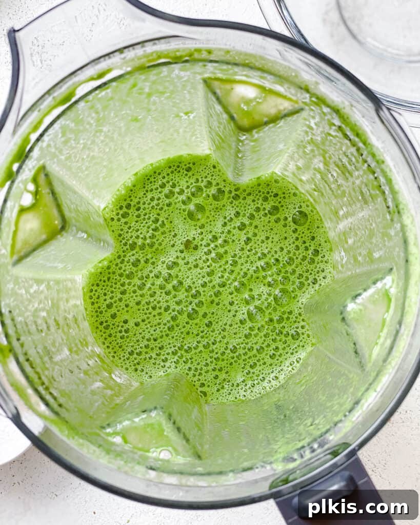 Green Power Banana Pancakes 4 A high-speed blender container with plant-based milk and fresh spinach, mid-blend, creating a smooth green liquid for the pancakes.