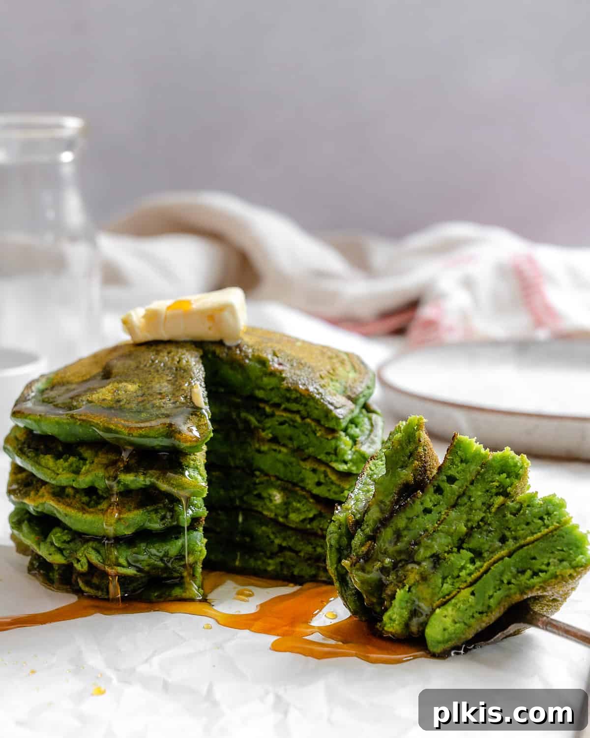 Green Power Banana Pancakes 8 A high-angle shot of a stack of vibrant green Banana Spinach Pancakes, topped with berries and maple syrup, ready to be enjoyed.
