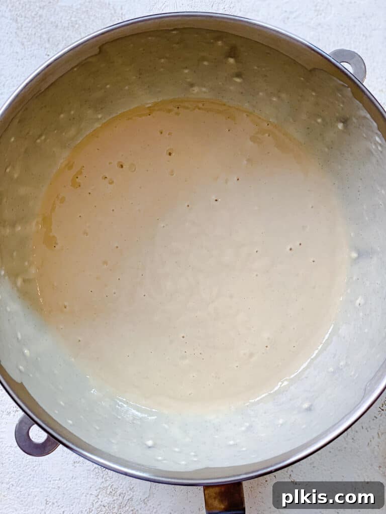 Effortless Vegan Vanilla Cupcakes 5 process shot of adding additional wet ingredients to cupcake mixture in bowl, highlighting the smooth texture of the batter