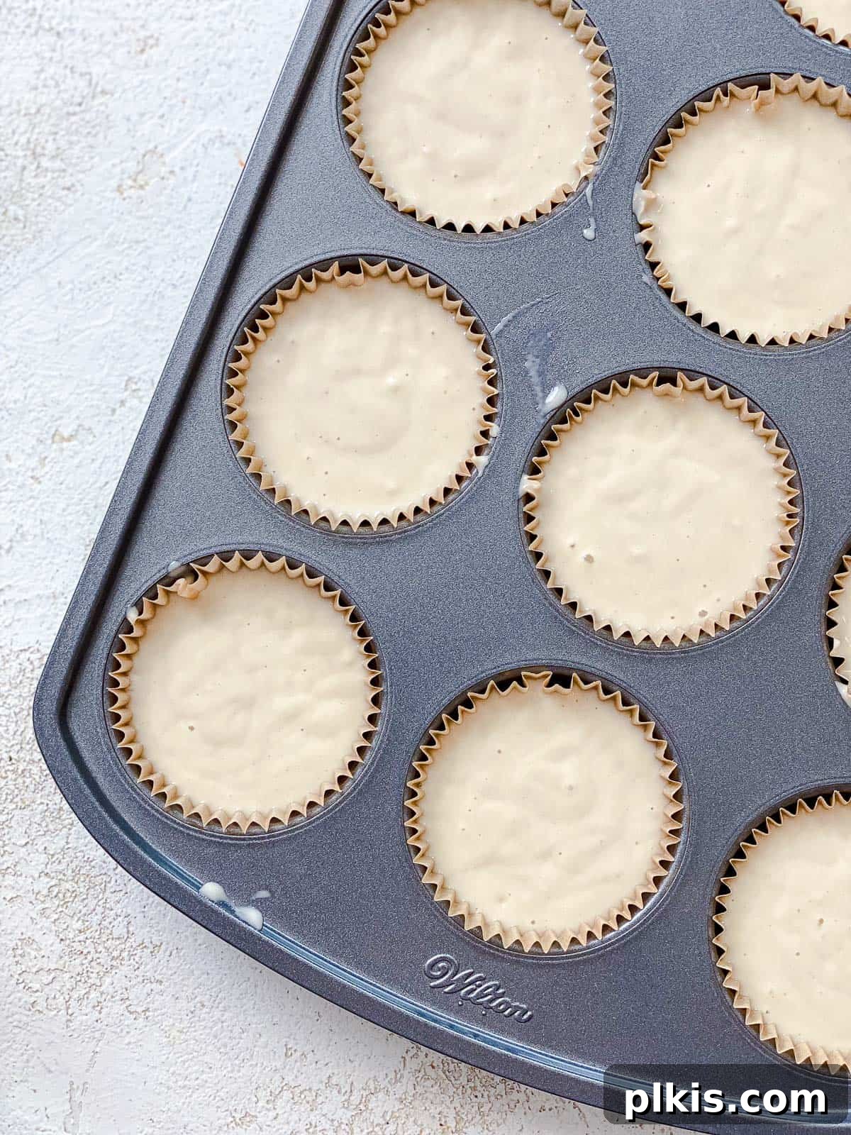 Effortless Vegan Vanilla Cupcakes 6 process shot showing addition of cupcake batter in muffin tin, demonstrating the ideal fill level of three-quarters full