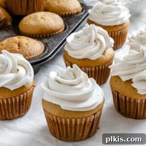 Effortless Vegan Vanilla Cupcakes 9 completed cupcakes spread out on white surface and in muffin tin