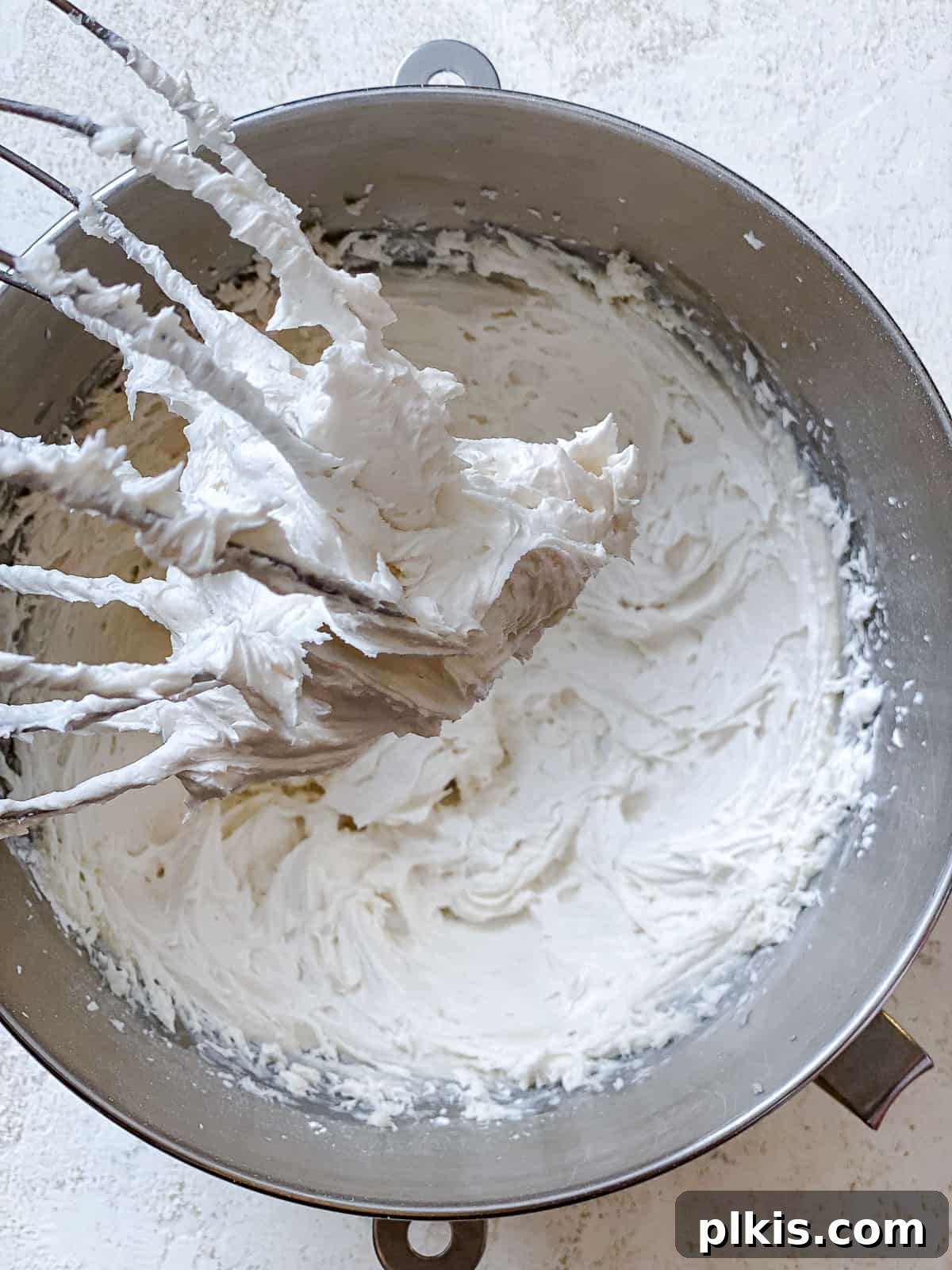 Velvety Vegan Vanilla Buttercream 5 Process shot showing powdered sugar being gradually added to creamed vegan butter in a mixing bowl.