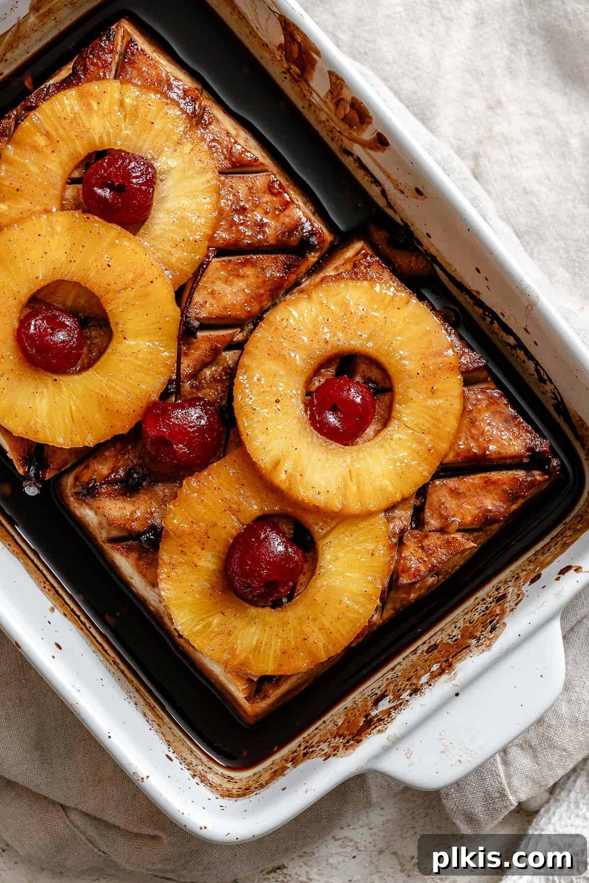 Golden Pineapple Glazed Tofu Ham 2 A beautifully baked Pineapple Glazed Tofu Ham in a baking dish, adorned with pineapple rings and maraschino cherries, ready to be served as a holiday centerpiece. It's sweet, savory, and so delicious, perfect for any festive table.