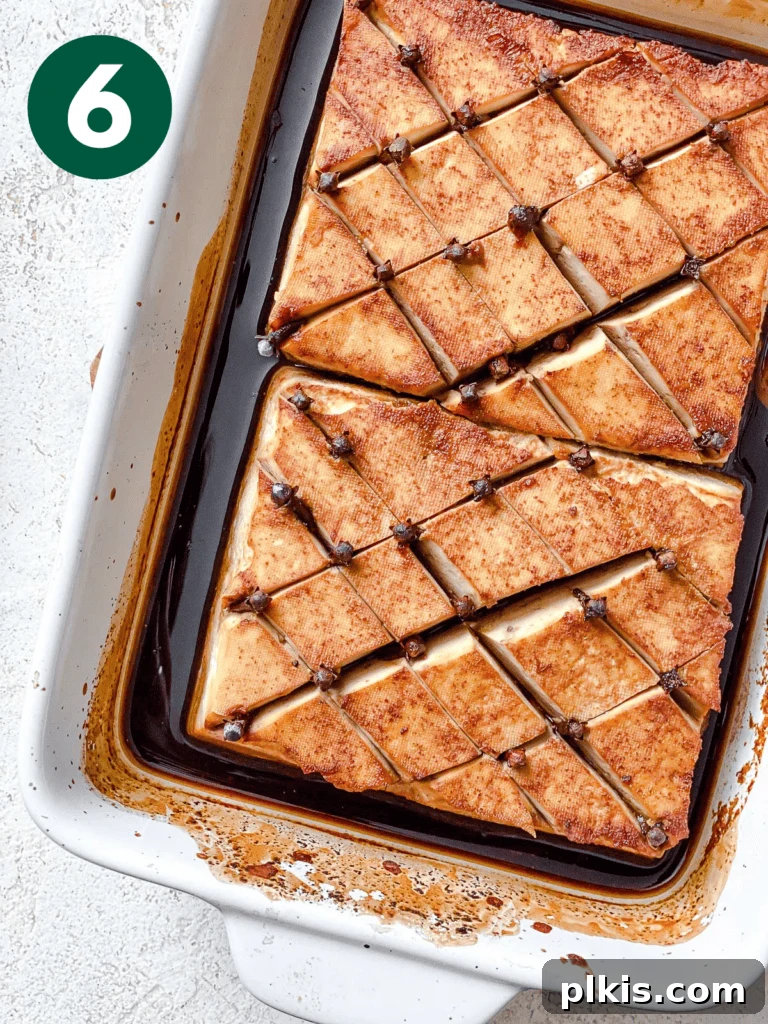 Golden Pineapple Glazed Tofu Ham 9 A post-baked Glazed Tofu Ham resting in a baking dish, showing its beautifully browned and slightly caramelized exterior before the final glaze and toppings are added.
