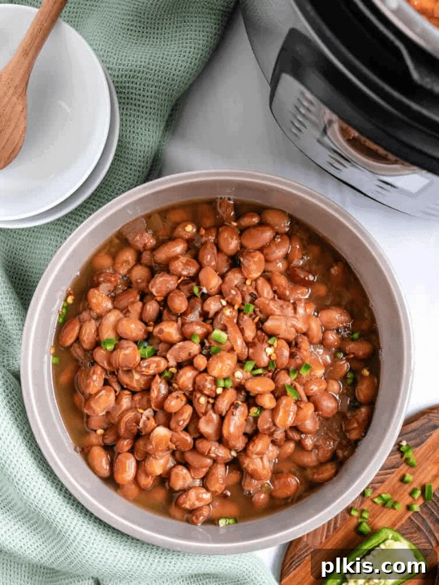 Perfectly Cooked Instant Pot Pinto Beans 15 completed pinto beans in a bowl against a white counter with a light green cloth and brown cutting board in the background