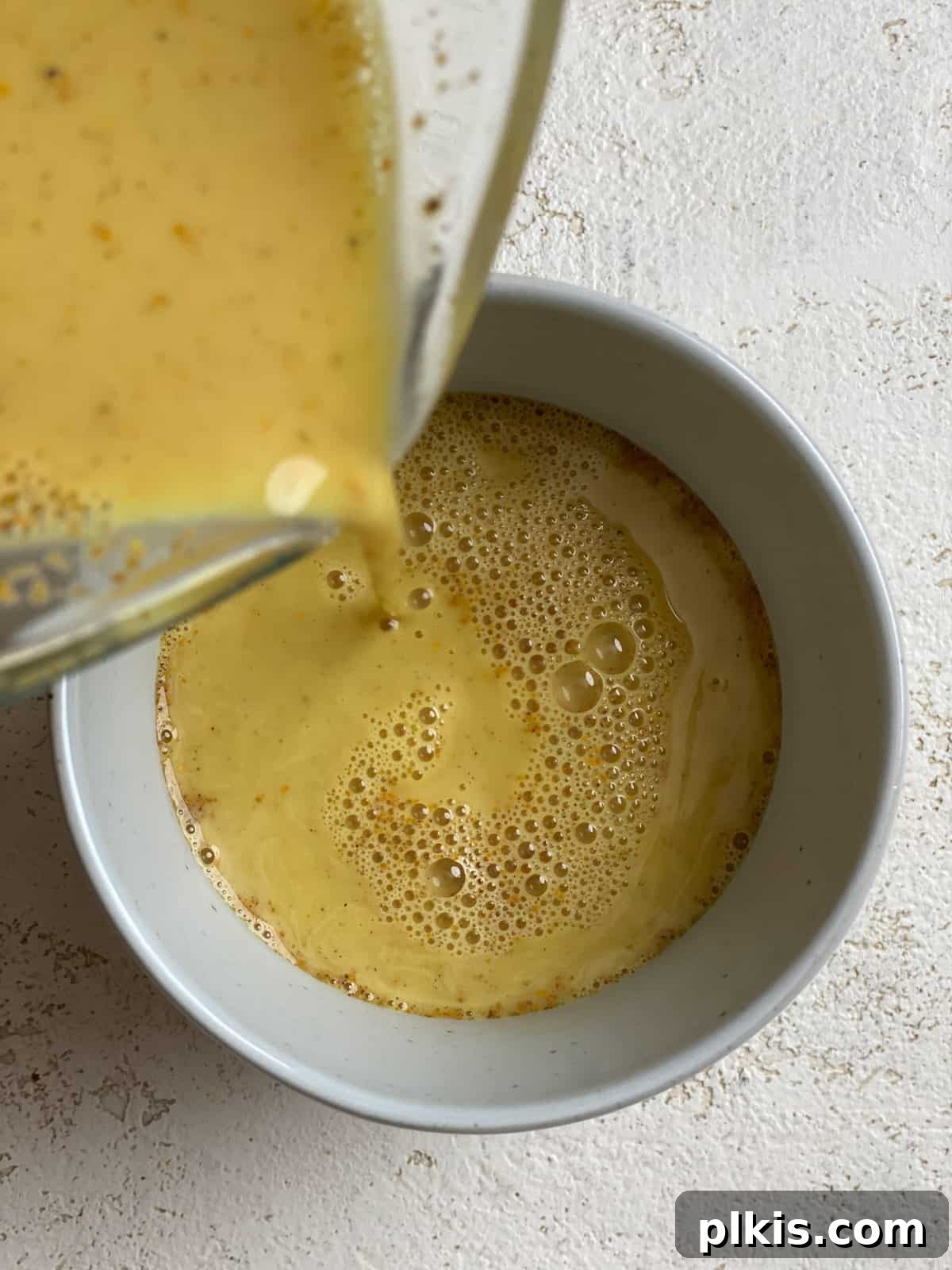 Golden Turmeric Elixir 8 Process shot of rich golden milk being carefully poured from a saucepan into a mug, ready to be enjoyed.