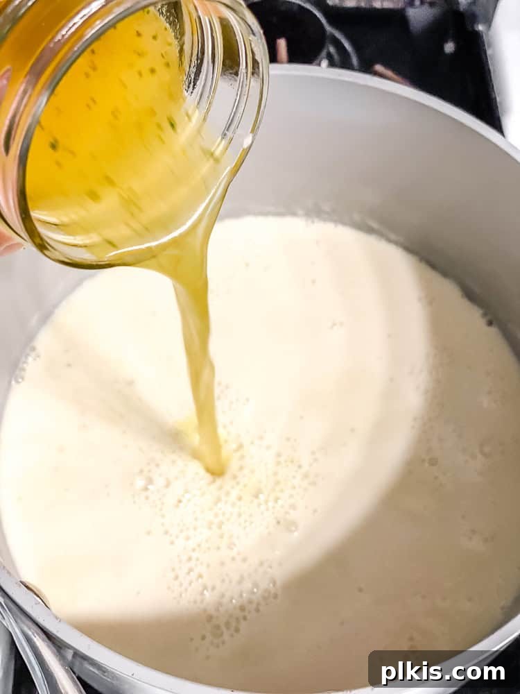 Decadent Dairy-Free Scalloped Potatoes 6 Plant-based milk and vegetable broth being poured into a pot containing a roux, to create the creamy sauce.