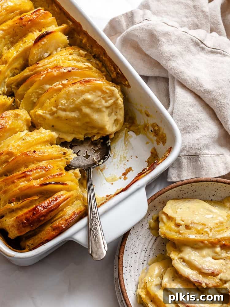 Decadent Dairy-Free Scalloped Potatoes 10 A spoon scooping a generous portion of creamy vegan scalloped potatoes from a white casserole dish onto a plate, highlighting the rich texture.